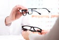 Optician giving new glasses to customer for testing and trying. Royalty Free Stock Photo