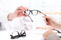 Optician giving new glasses to customer for testing and trying. Royalty Free Stock Photo