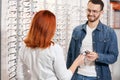 Optician giving a new pair of reading glasses to cheerful bearded patient. Royalty Free Stock Photo