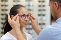 Optician helping client to fit eyeglasses Royalty Free Stock Photo