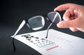 Optician holding glasses. Eyesight test chart in the background. Royalty Free Stock Photo