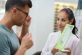 optician holding mirror for customer to appraise eyeglasses