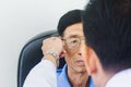 Optician male hands put glasses on elderly man testing his eye Royalty Free Stock Photo