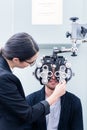 Optician and man at eye examination with phoropter