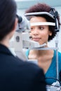 Optician measuring women eyes with refractometer