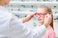 Optician putting glasses to girl at optics store Royalty Free Stock Photo
