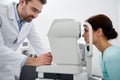 Optician with tonometer and patient at eye clinic