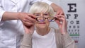 Optician wearing elderly female patient new glasses, vision treatment, health