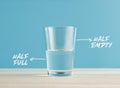 Optimism and Pessimism concept. Water glass with the words half full and half empty Royalty Free Stock Photo