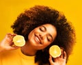 Optimist Young female model of afro appearance. Clean, even skin of the face. In the hands of citrus, orange.