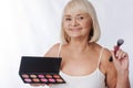 Optimistic aged woman using a rouge palette Royalty Free Stock Photo