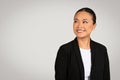 Optimistic Asian businesswoman in a black suit looking away with a pleasant smile