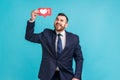 Optimistic bearded man wearing official style suit, holding social network Heart Like icon over head Royalty Free Stock Photo