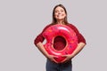 Optimistic cheerful girl holding rubber ring pink donut and looking at camera with toothy smile, enjoying summer