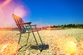 Optimistic cheerful image of a simple folding chair on a gravel beach backlit with sun reflections on the coast of Istria, Croatia