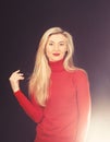 Optimistic girl touches her blond hair. Lady in red blouse on dark background. Royalty Free Stock Photo