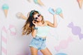 Optimistic girl wearing tank-top and trendy accesorries dancing with smile enjoying music. Portrait of joyful young Royalty Free Stock Photo