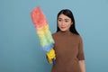 Optimistic glad asian housewife in gloves holding dust brush