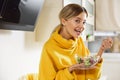 Optimistic lady smiling to the camera while eating salad