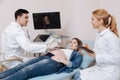 Optimistic medical colleagues providing checkup for pregnant patient