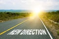 Optimistic road landscape with sunlight ahead and New Direction inscription. Motivational inscription on the road going forward. Royalty Free Stock Photo