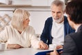 Optimistic senior couple having conversation with advisor at home