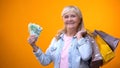 Optimistic senior lady showing shopping bags and euro banknotes, consumerism Royalty Free Stock Photo