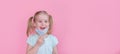 Optimistic, smiling happy little girl taking off the medical mask from face on a pink background showing end of the pandemia.