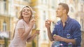 Optimistic young couple blowing bubbles and laughing together, romantic date