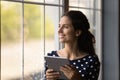 Optimistic young lady look at window dream with digital tablet Royalty Free Stock Photo