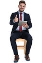 Optimistic young man holding tab and making thumbs up sign