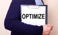 The OPTIMIZE is written on a white sheet held by a man standing sideways Royalty Free Stock Photo