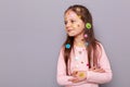 Optmistic smiling little girl covered colorful kid's stickers standing isolated over gray background lookign away and