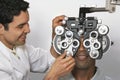 Optometrist Adjusting Panels Of Phoropter While Examining Patient Royalty Free Stock Photo