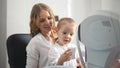 Optometrist checks child`s eyesight - mother and child in ophthalmologist room