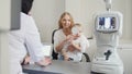 Optometrist checks child`s eyesight - mother and child in ophthalmologist room