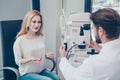 Optometrist consultation. Blond lady patient is talking to brunet bearded male doctor optician in his office about the diagnosis