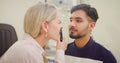 Optometrist doing an eye test on a patient in a clinic. Female optician assessing the vision of a young man with a