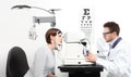 Optometrist examining eyesight patient in optician office on wh