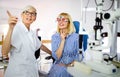 Senior woman optometrist examining patient in modern ophthalmology clinic Royalty Free Stock Photo