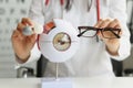 Optometrist woman holding glasses near anatomical model eye