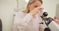 An optometrist using a microscope to examine a pair of glasses, to calibrate and configure prescription lenses. Female