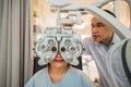 Optometrist using phoropter to check eyesight value for client eyeglasses