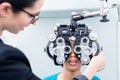 Optician and woman at eye examination with phoropter Royalty Free Stock Photo