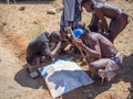 Opuwo, Namibia - July 25, 2015: Group of Himba men and boys leaning over and looking at map of Namibia