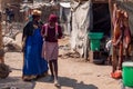 Old Woman in Traditional Herero Clothing and Young Schoolgirl in School Uniform on the local Market in Opuwo