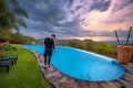 Girl in black standing beside a swimming pool in a luxury resort at sunset Royalty Free Stock Photo
