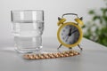 Oral contraceptive pills, glass of water and alarm clock on white table Royalty Free Stock Photo