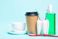 Oral dental hygiene. Healthy white tooth and dentist mirror near toothbrush, mouthwash, tea cup and plastic thermo cup of coffee