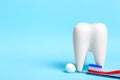 Oral dental hygiene. Dental mirror with toothbrush near healthy white tooth model on light blue background. Free space for your